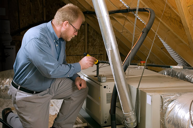 Furnace Maintenance and Winter Energy Saving Tips. A technician working on a furnace.