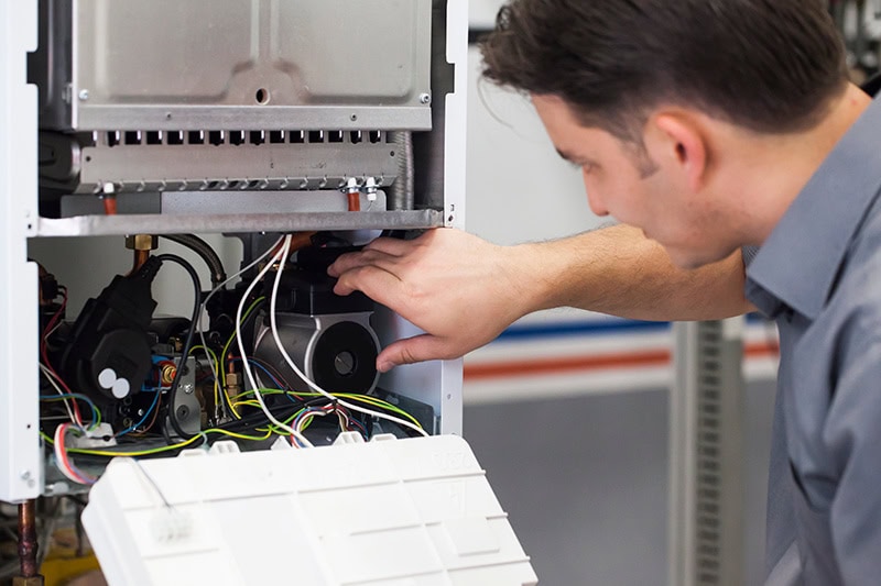 4 Important Heat Pump Maintenance Tips. A technician repairing a heat pump.