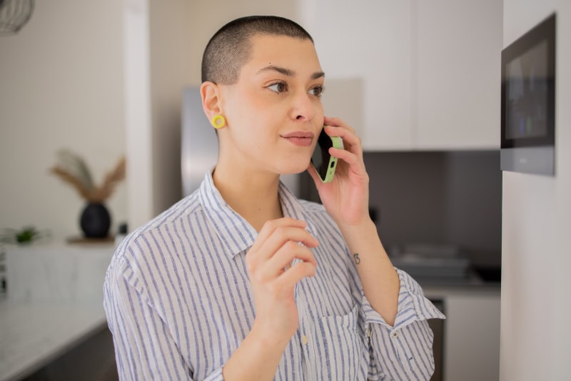 Young woman adjusts the temperature at home with a device on the wall