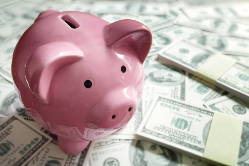 Piggy bank on top of dollar bills.